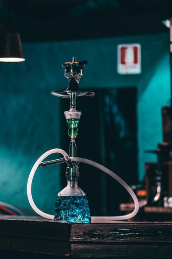A vertical shot of the Italian hookah with glass flask on the wooden surface in the bar of Milan