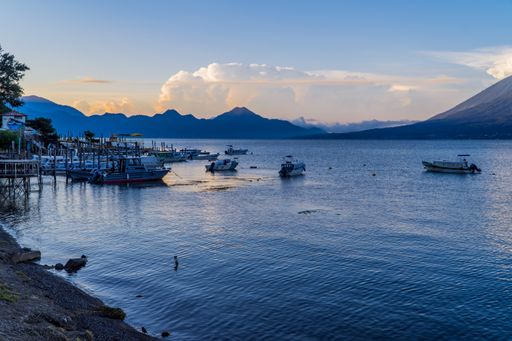Many Boats in the lake port surrounded by mountains.