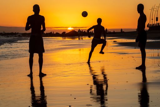A silhouette of young people playing sand football at sunset on Ondina beach in Salvador, Brazil
