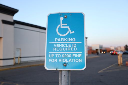 A closeup shot of a handicap parking sign on the street against a blurred background
