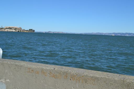 A wide shot of the sea surrounded by mountains in the distance under a clear blue sky