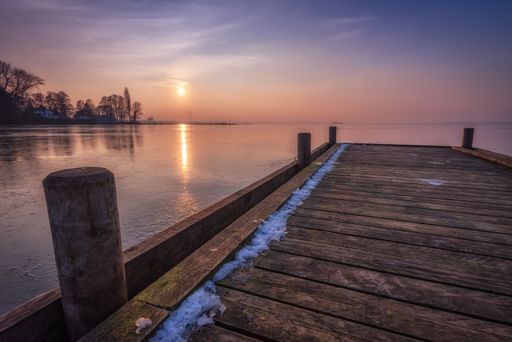 A pier at steinhude lake in winter during sundown