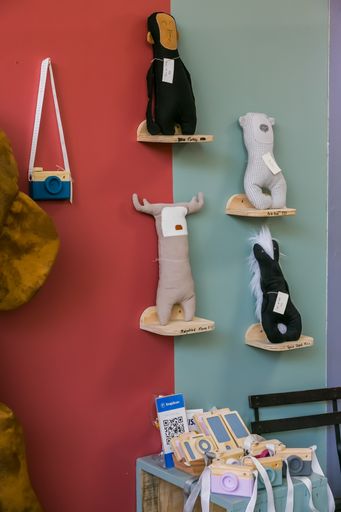 A vertical shot of handmade fabric toys on wooden desks hung on the wall.