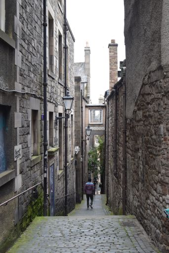 A vertical shot of a narrow path and a man walking down