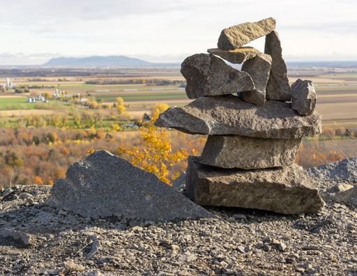A close-up shot of stacked stones with fields in the background in fall on a sunny day