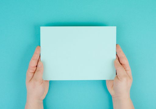Woman holds a blank sheet of paper, blue colored background, empty copy space for text, minimalism