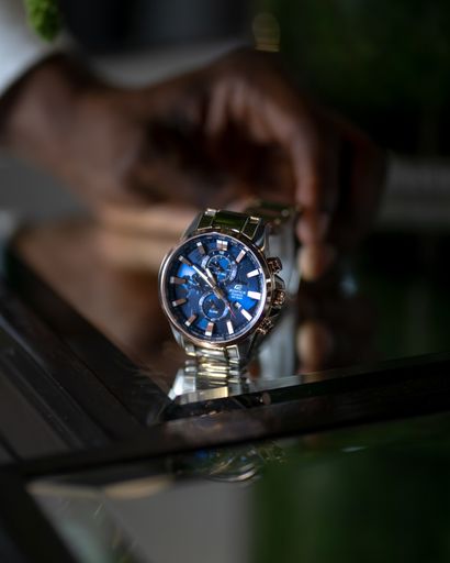 A vertical selective closeup shot of a person holding a gray and blue wristwatch