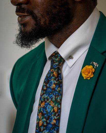 A vertical closeup shot of an African person with beard wearing gray suit with colorful tie