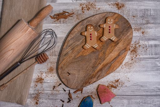 Two gingerbread cookies on a wooden board with tools on a wooden background