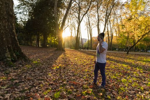 A young Spanish guy standing in the autumn park on a sunny day