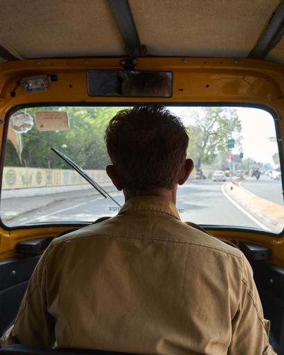 A vertical shot of the back of a bus driver on the road under the sunlight at daytime