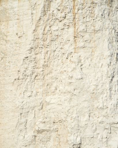 A vertical closeup of a rough white wall under the sunlight - cool for backgrounds