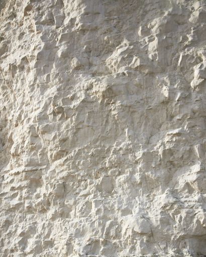 A vertical closeup of a rough white wall under the sunlight - cool for backgrounds