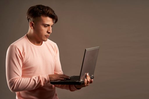 A Latin man using a laptop on isolated gray background