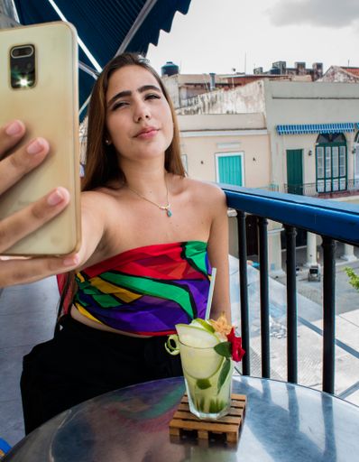 A vertical shot of a young woman taking a selfie on the phone on a balcony, Old Havana, Cuba