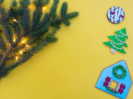 Homemade gingerbread cookies isolated on a yellow background with spruce branches and lights