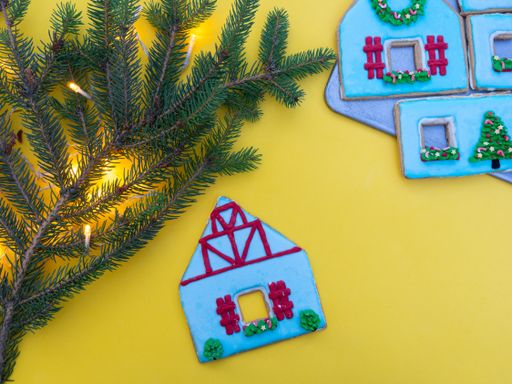 Homemade gingerbread houses isolated on a yellow background with spruce branches and lights