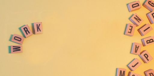 The word WORK, taken from a pile of wooden letter blocks with yellow background and copy space