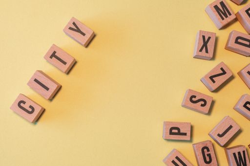 The word CITY, taken from a pile of wooden letter blocks with yellow background and copy space