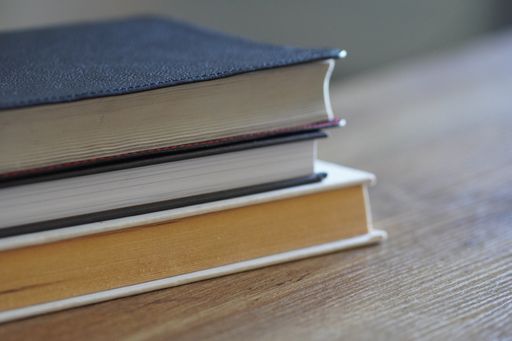 A stack of three books on a wooden table