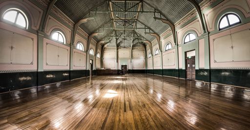A beautiful shot of a hall with big windows reflecting on the wooden floor