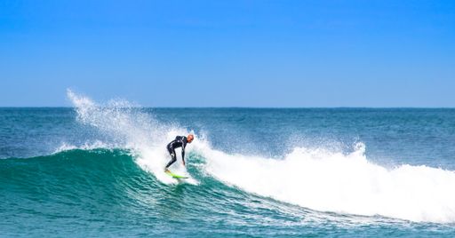 A man surfing on big waves on the island of Santa Catarina at Mole beach under a blue sky on a sunny day