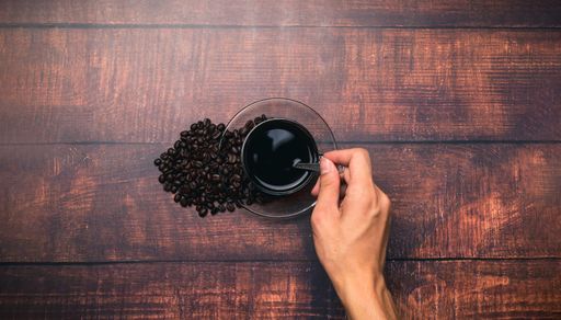 A Top view of a Coffee mug and coffee beans on a wooden surface