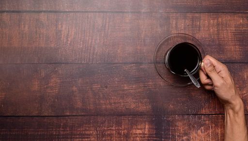 A Top view of a Coffee mug and coffee beans on a wooden surface