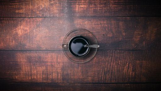 A Top view of a Coffee mug and coffee beans on a wooden surface