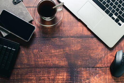 A Top view of a coffee mug, notebook, and smartphone on a wooden surface in a working atmosphere