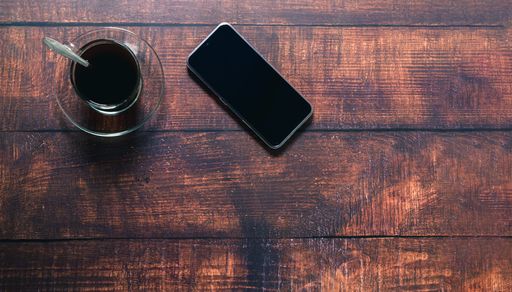 A Top view of a coffee mug and smartphone on a wooden surface in a working atmosphere