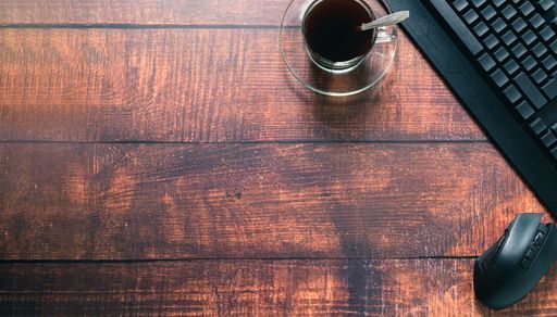 A top view of a Coffee cup, keyboard, mouse at the desk