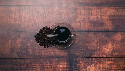 A top view of a Coffee mug and coffee beans on a wooden surface