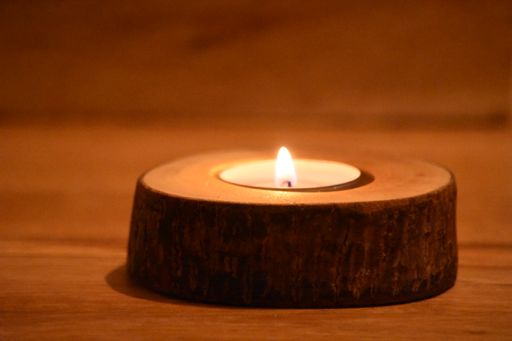 A candle burning on a wooden table