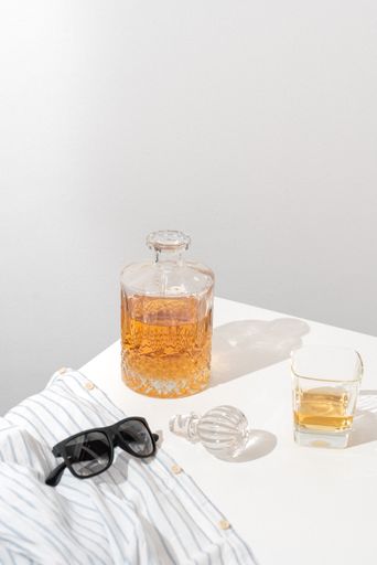A Closeup of a beer and sunglass on a table isolated on a white background