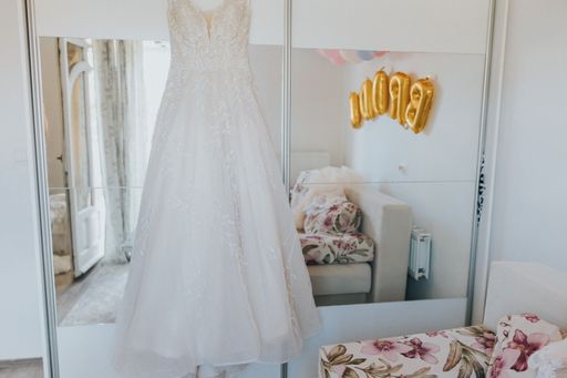 The bride's dress hanging on the cornice of the wardrobe in a room - wedding preparation