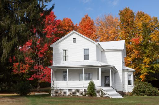 A beautiful view of an old white house surrounded by fall colour trees in Accident Maryland