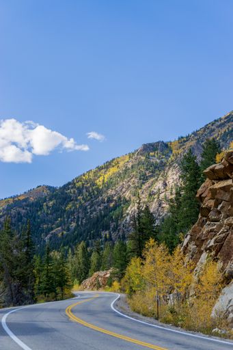 A vertical shot of an asphalt road surrounded by mountains and lush vegetation