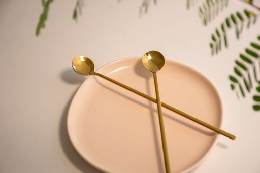 A high angle shot of a plate with two brass spoons in it