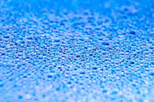 A selective focus shot of colorful reflective water drops on a digital disc surface. various RGB LED lights illuminate the scene.
