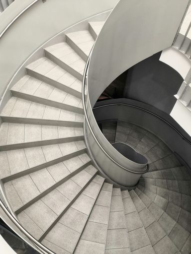 a vertical greyscale shot of round staircase with interesting modern architecture