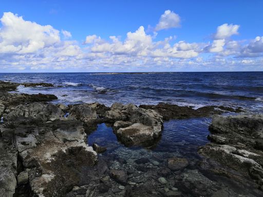 a view of a beautiful calm beach with rocks in Malta captured on a sunny day