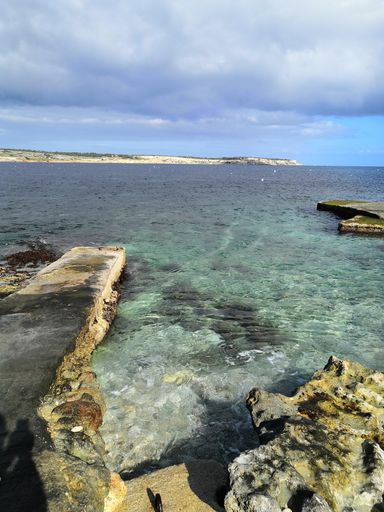 a vertical shot of a beautiful beach with rocks in Malta captured on a cloudy day