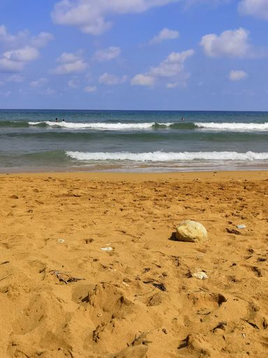 a vertical shot of a calm sea captured from the beach on a bright sunny day