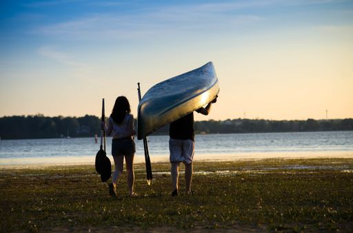 The behind shot of the couple with a sea kayak walking towards the sea