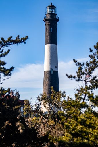 A vertical shot of the famous Fire Island lighthouse against a blue cloudy sky on a sunny day