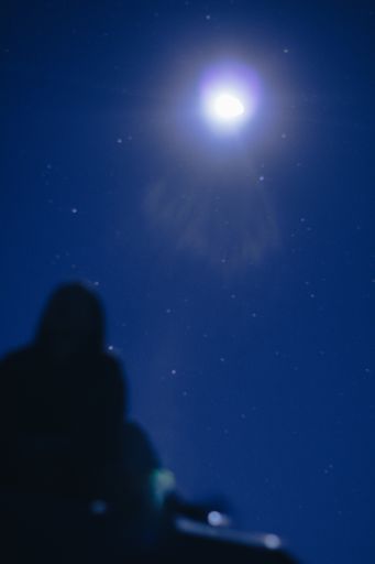 A vertical shot of the beautiful white moon shining in the blue sky full of stars