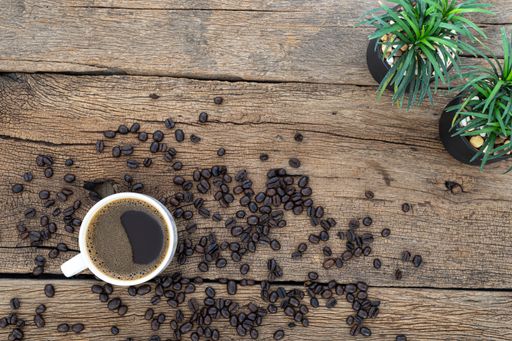 A top view of a cup of coffee with coffee beans on a wooden table