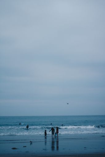 A vertical shot of a beach under a gloomy gray sky in the evening with a family getting ready to leave