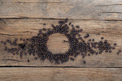 A top view of an empty cup space in the coffee beans on a wooden table
